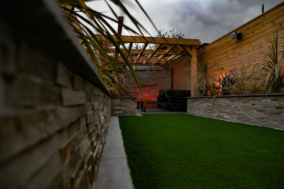 A lush artificial turf lawn flanked by a stone retaining wall — perfect for Denver sloped yards.