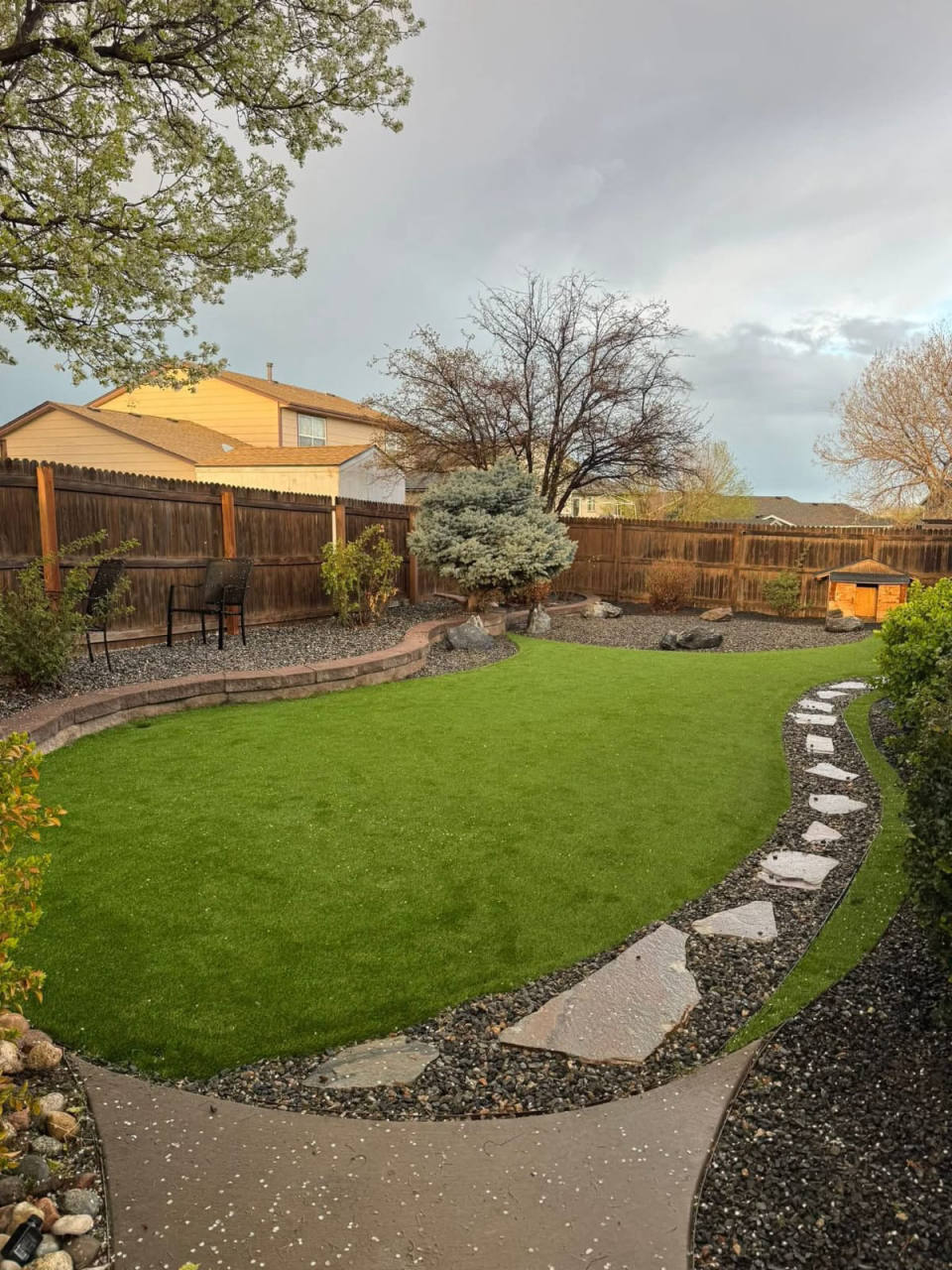 Artificial turf backyard with flagstone path and mature trees — artificial turf in Denver, CO
