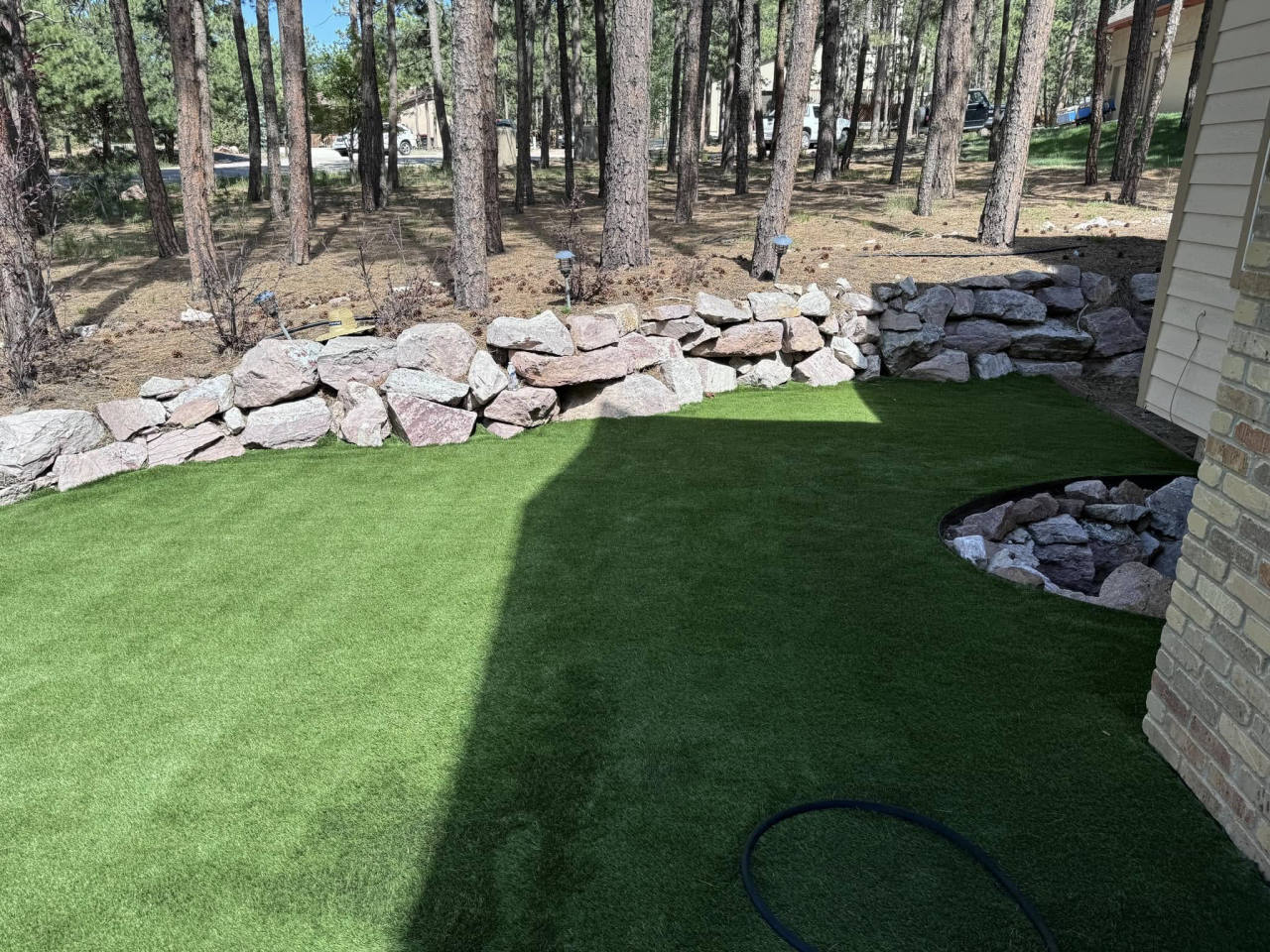 Artificial turf lawn bordered by a natural rock wall and pines — artificial turf in Parker, CO