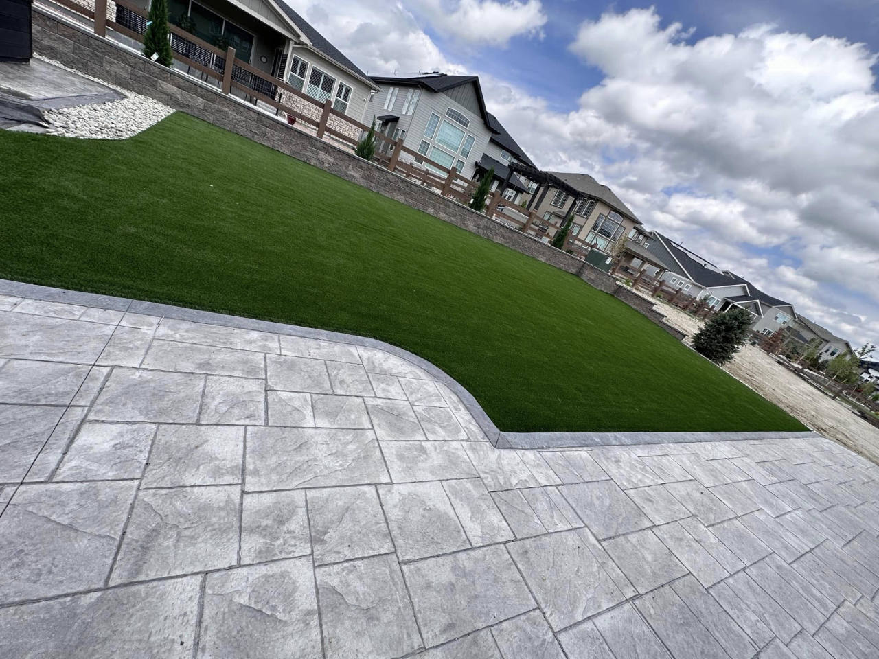 Artificial turf hillside lawn with a stamped concrete patio — artificial turf in Highlands Ranch, CO