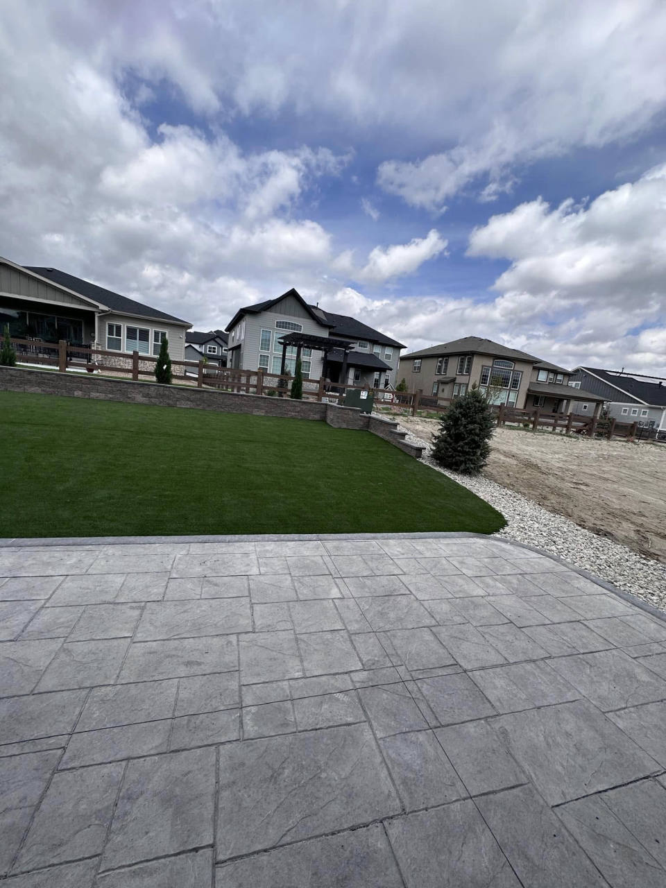 Sloped artificial turf lawn meeting a stamped concrete patio — artificial turf in Centennial, CO